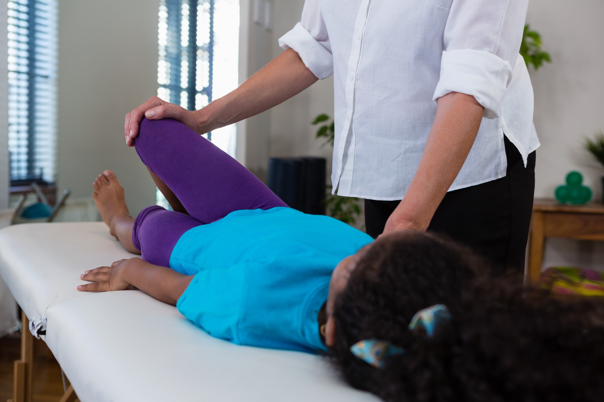 Physiotherapist giving leg massage to a girl patient